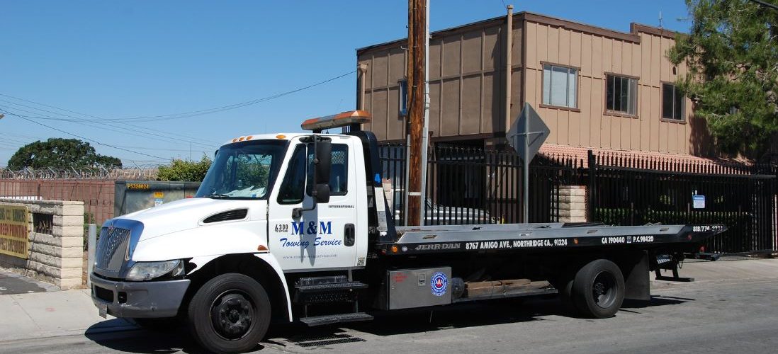 White Flatbed Tow Truck In Front Of Building