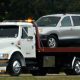 White Flat Bed Towing Service Truck Carrying A Vehicle