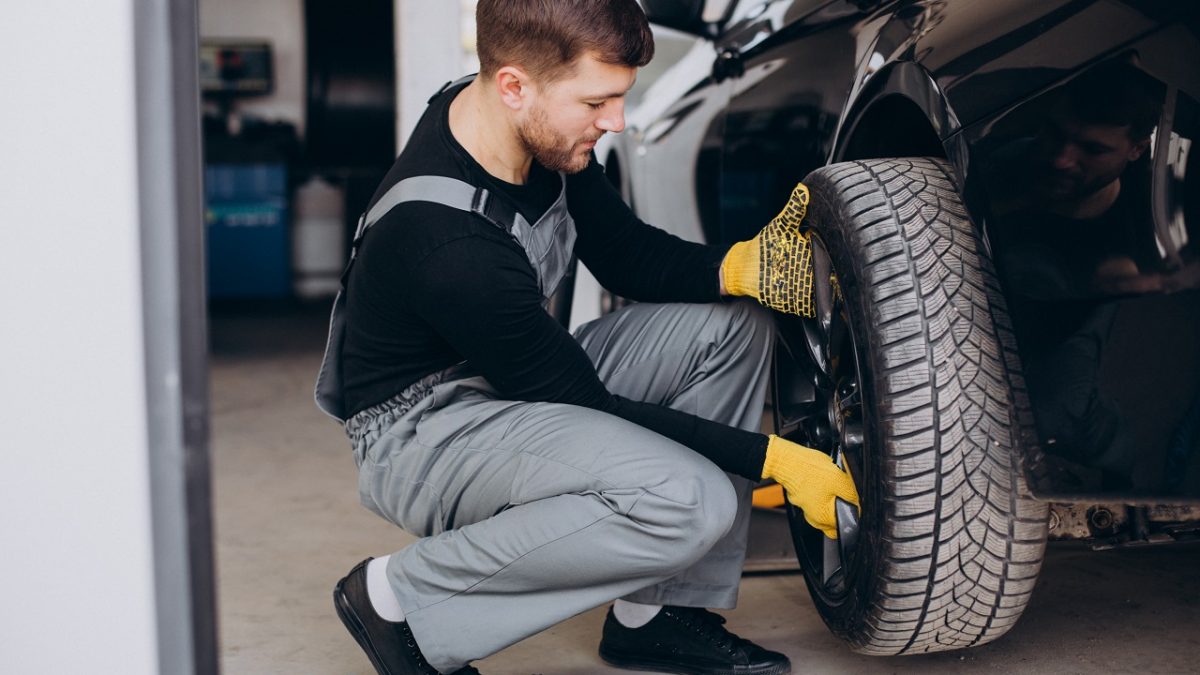 Car mechanic rotating car tires for tire maintenance