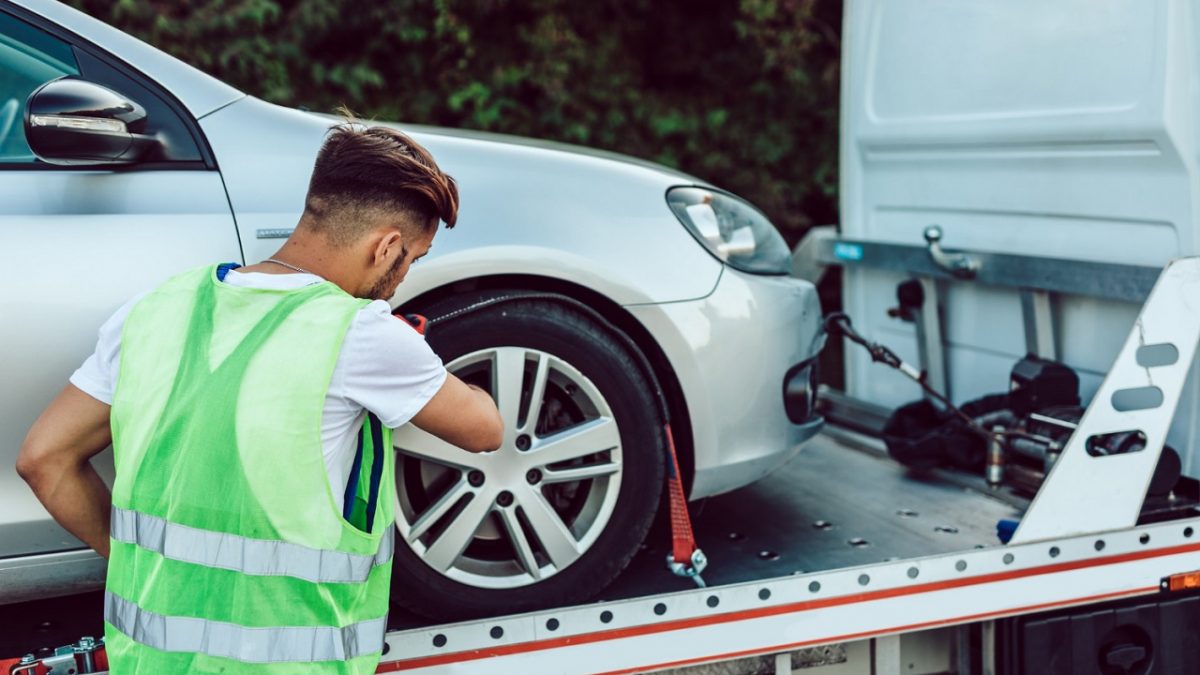man securing car on a flatbed
