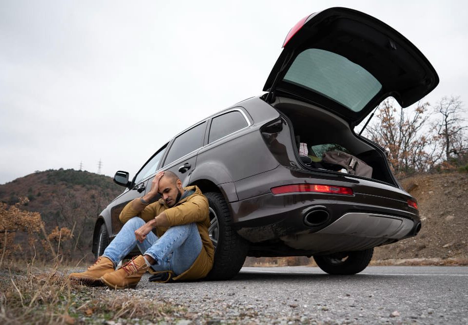 man with a broken car on the side of the road